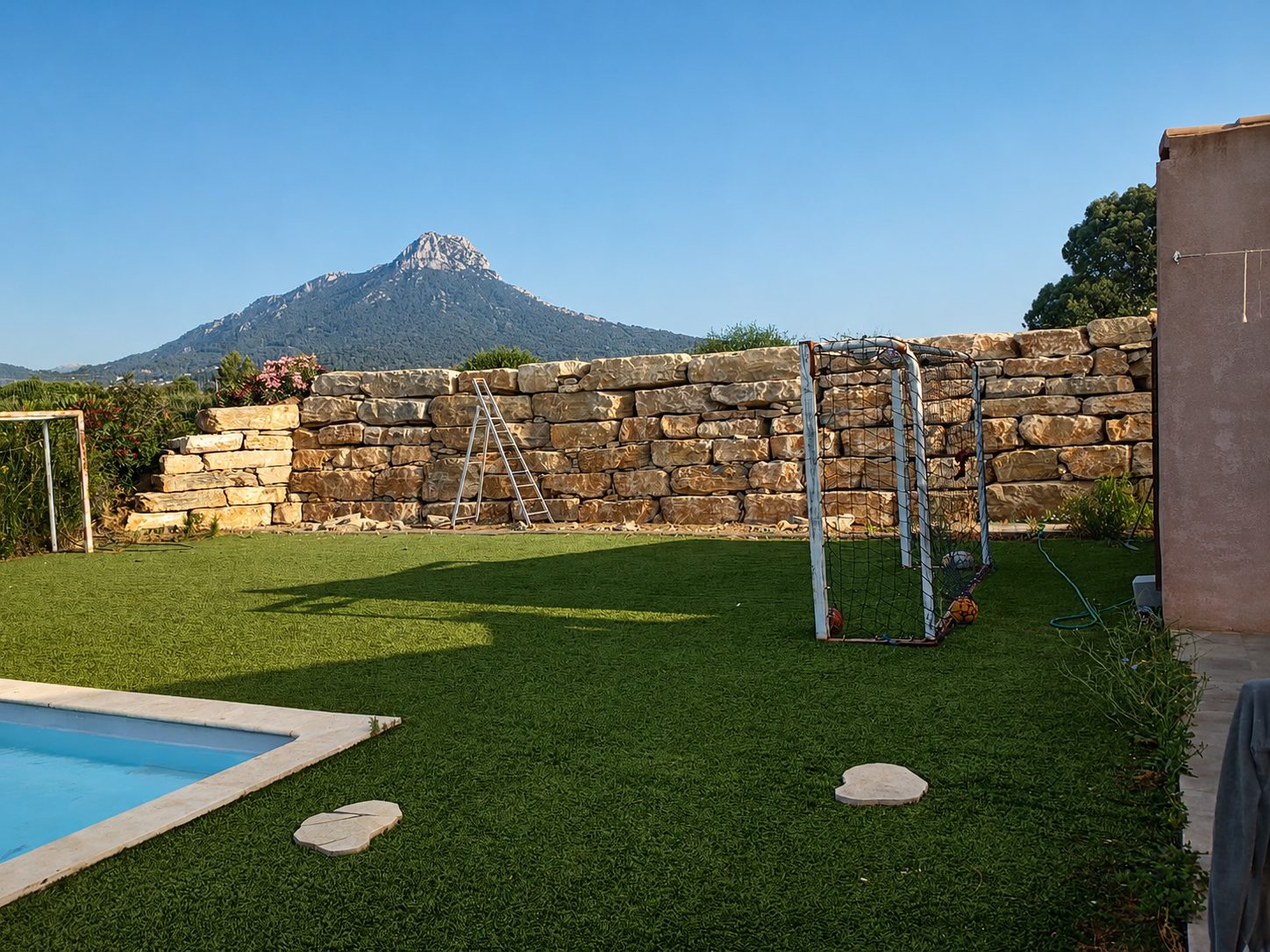 Mur d'enrochement de soutènement en blocs calcaires bordant un jardin